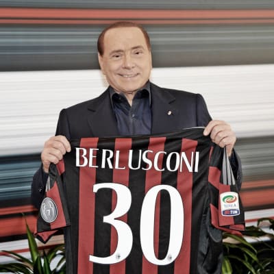 Silvio Berlusconi håller upp en Milantröja med nummer 30 på.