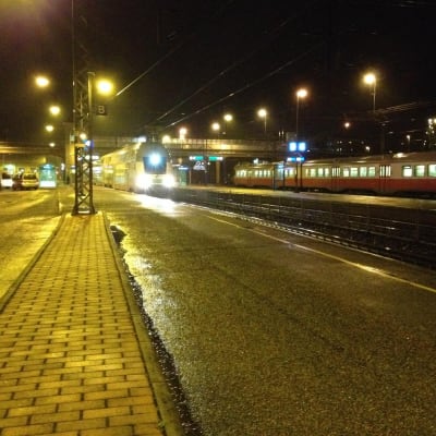 Två tåg på järnvägsstationen i Karis en mörk höstkväll.