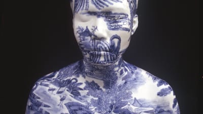 Ett porslinshuvud i glaserad porslin med blåvitt landskapsmotiv