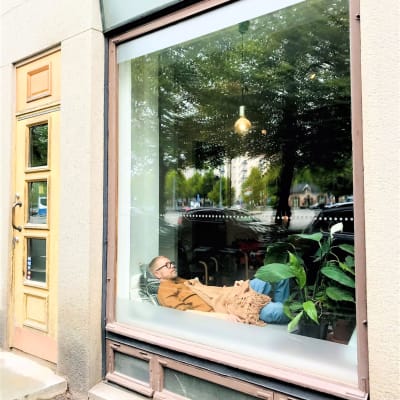 Mies makaa liiketilan ikkunalla.