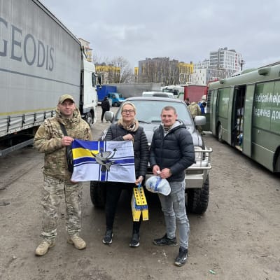 En kvinna och två män vid en bil som fört förnödenheter till krigsdrabbade Ukraina.
