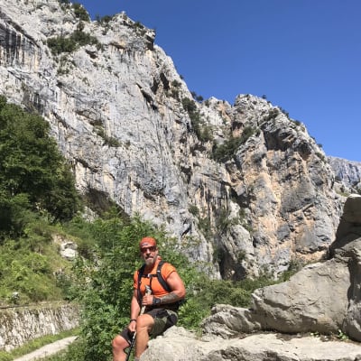 Björn Roos sitter på en sten i ettt bergit landskap.