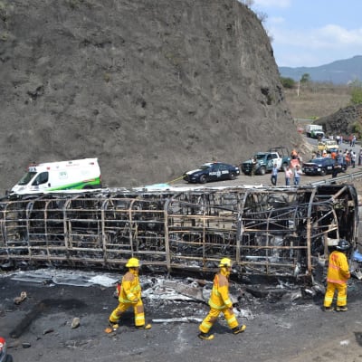 En buss ligger på sidan efter att ha krockat och börjat brinna i Mexiko.