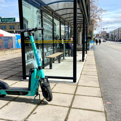 Elsparkcykel står parkerad på en trottoar.