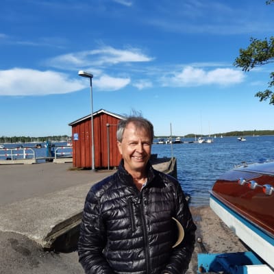 En man som står i en hamn bredvid en båt. 