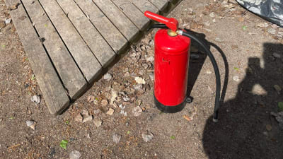 Dörrarna till ett stort lagerutrymme har öppnats. I förgrunden står en röd skumsläckare, vars pulver har sprutats ut på marken.