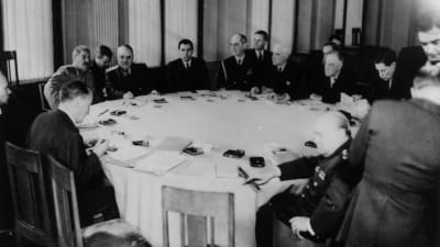 Män i kostymer sitter runt ett bord.
