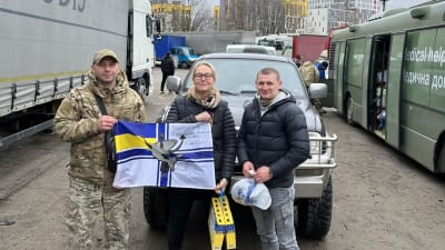 En kvinna och två män vid en bil som fört förnödenheter till krigsdrabbade Ukraina.