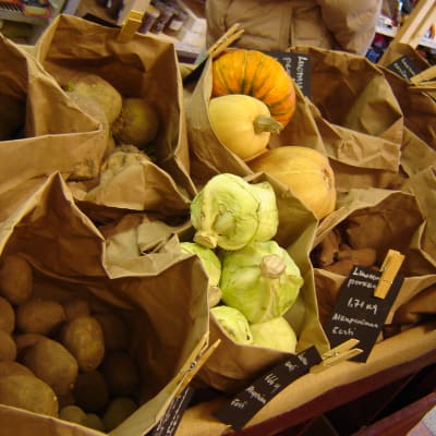 Olika grönsaker i papperspåsar på en matmarknad.