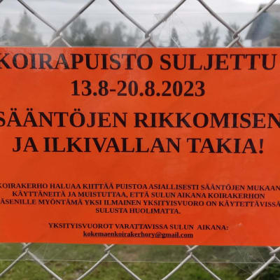 Punainen kyltti, jossa kerrotaan Kokemäen koirapuiston sulkemisesta sääntörikkomuksen takia.