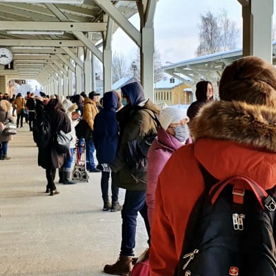 Mänskor väntar på ett försenat tåg på en full perrong på tågstation i Tartu, Estland.