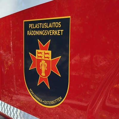 En brandbil med Räddninsgverket logo på dörren finns vid ett trähus med en skylt om att det är privat område. En brandman kommer gående mot brandbilen.