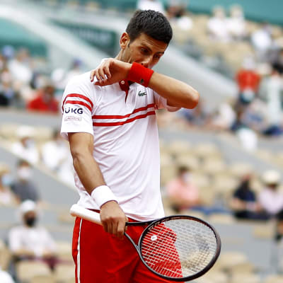 Novak Djokovic torkar sitt ansikte mot armen.