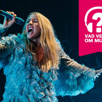 Ellie Goulding blundar och sjunger i en mikrofon som hon håller i handen.