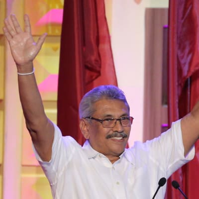 Gotabhaya Rajapaksa ler och sträcker upp händerna i luften. 