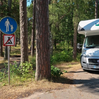Bild av en husbil som är parkerad bredvid en skylt som förbjuder att slå läger. 