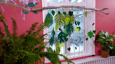 Ett insynsskydd gjort av gröna blad i filttyg hänger vid ett fönster