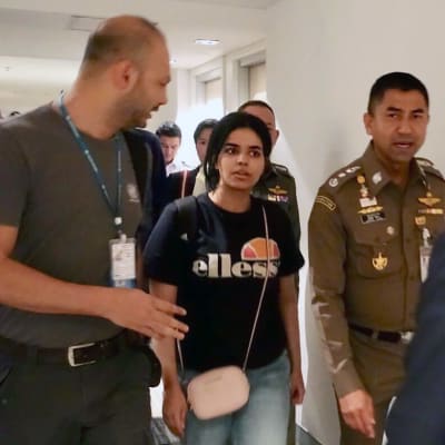 Rahaf al-Qunun tillsammans med en polis och en annan man.