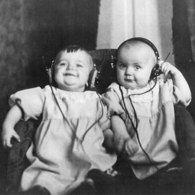 Kaksostyttövauvat kuuntelevat radiota kuulokkeilla 1920-luvun puolivälissä.