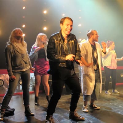 Joukko nuoria tanssii värivaloissa teatterin näyttämöllä