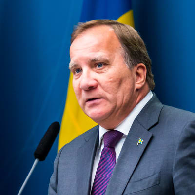 Stefan Löfven framför Sveriges och EU:s flaggor.