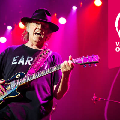 Neil Young har hatt på huvudet och han spelar elgitarr.