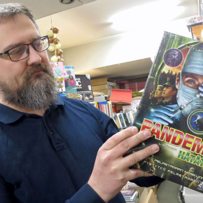 Mies ottaa kirjakaupassa lautapelin hyllystä jossa lukee Pandemic
