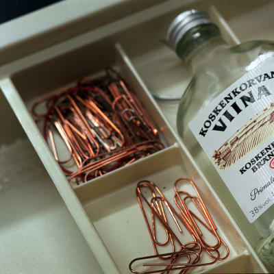 En flaska med Koskenkorvan viinaa ligger i en skrivbordslåda tillsammans med en massa gem.