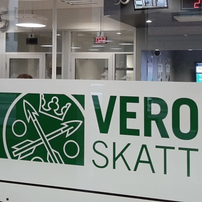 En skylt med texten Vero Skatt, på glasdörren in till ett skattekontor.