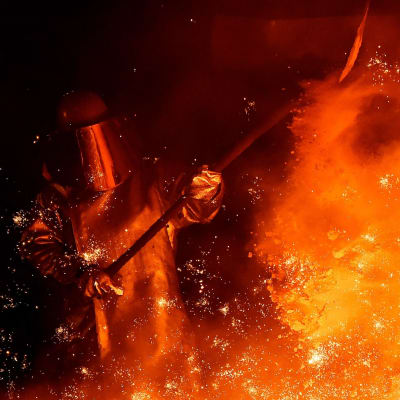 Dramatisk bild av skyddsklädd stålarbetare mitt i de gula flammorna på tyskt stålverk