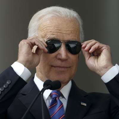 Biden tar på sina solglasögon vid en tillställning på Harvard.
