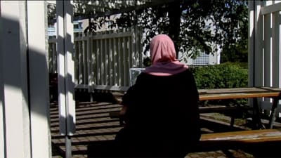 Invandrarkvinna sitter på bänk
