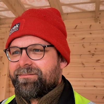 En man i en halvfärdig stockstuga.