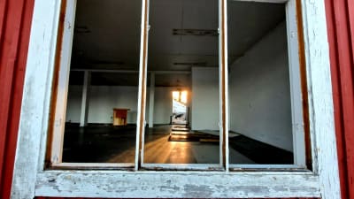 Insidan av ett tomt hus som håller på att rivas, fotograferat genom ett fönster.