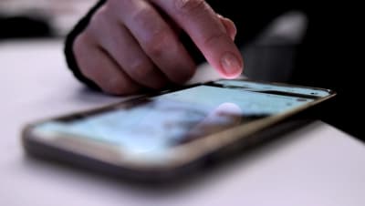 Närbild på ett finger på en smarttelefon. 