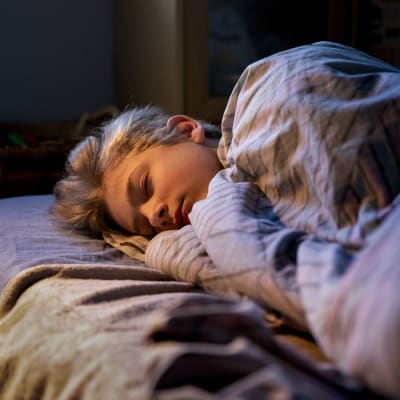 En tonårspojke sover i sin säng.