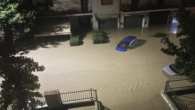 Bil på en översvämmad väg i Italien.