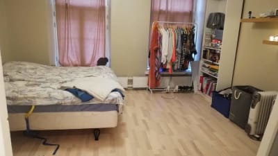 Städat sovrum med kläderna i ställning och bäddad säng