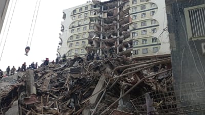 Människor och räddningspersonal söker efter offer på platsen för en kollapsad byggnad efter en kraftig jordbävning i Turkiet.