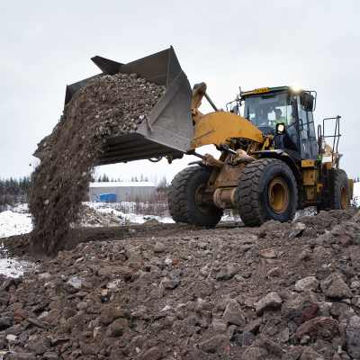 Kauhakuormaaja levittää betonimursketta tiepohjaan.