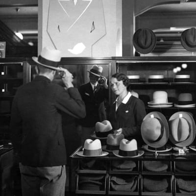 Kundbetjäning på hattavdelningen år 1930. Man köper hatt av kassabiträde i Stockmann.
