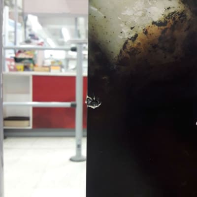 Ett kulhål i en reklamskylt efter ett skott i matbutik. 