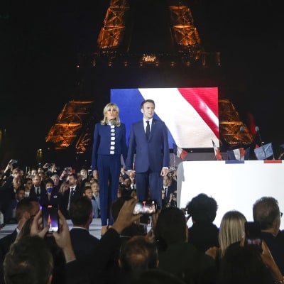 Emmanuel Macron och hans fru Brigitte Macron framför sina anhängare med Eiffeltornet i bakgrunden.