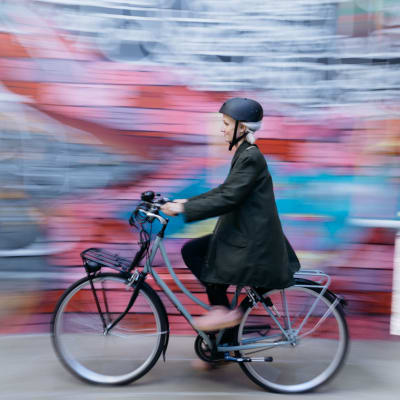 Nainen pyöräilee värikkään graffitin ohi