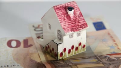 Litet prydnadskeramikhus står på eurosedlar.