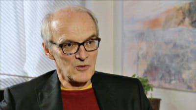Professor i arbetsrätt, Seppo Koskinen i röd tröja och svart kavaj.