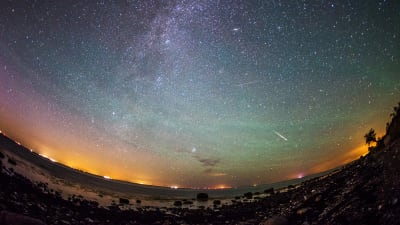Stjärnfall från perseiderna på en gul, lila, grön och blåfärgad himmel över den tyska ön Fehmarn i augusti 2015.