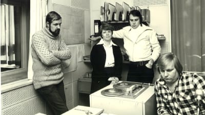 Fyra personer kring en radiobandspelare. De heter Rolf Wessman, Dorrit Krook, Kenneth Gröndahl och Carl-Henrik "Cucke" Ekström.