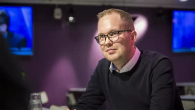 Forskaren Sakari Taipale sitter framför en lila vägg och ser oroad ut.