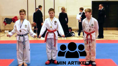 Tre taekwondokillar står bredvid varandra. Arseny Ignatiev i mitten.